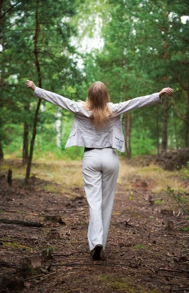 Mujer joven caminando en un bosque — Foto de Stock