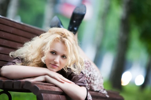 Mladá žena ležící na lavičce — Stock fotografie
