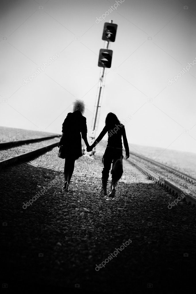 Two goth women walking far on railway