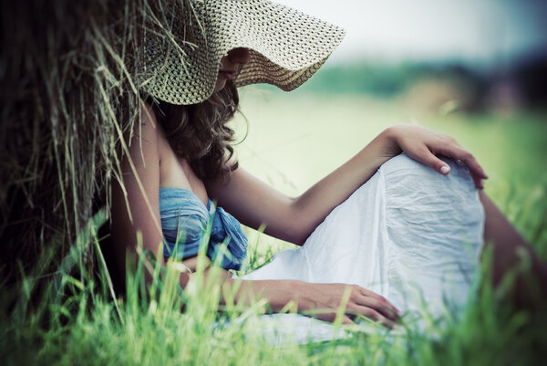 Young pensive woman resting on a field.