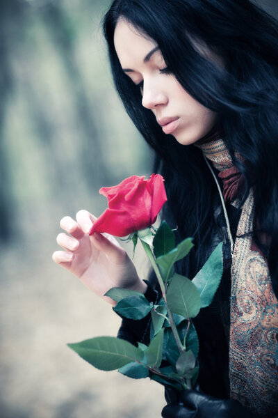 Young brunette woman with red rose portrait. Soft colors.