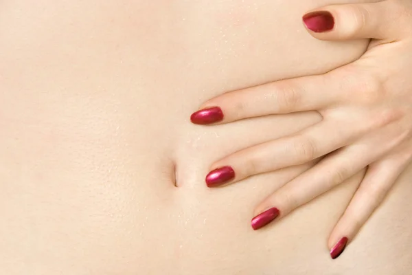 Mano con uñas rojas en la barriga — Foto de Stock