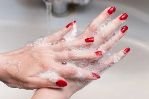 Se laver les mains avec des ongles rouges — Photo