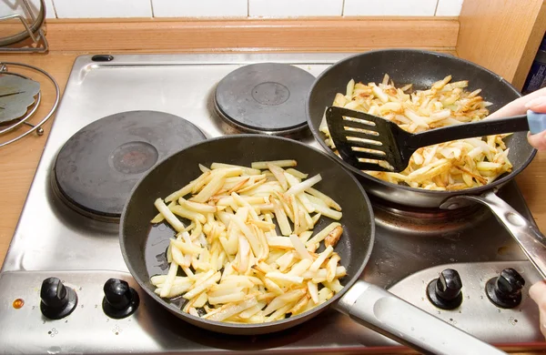 Frying potatoes on two pans — Stock Photo, Image