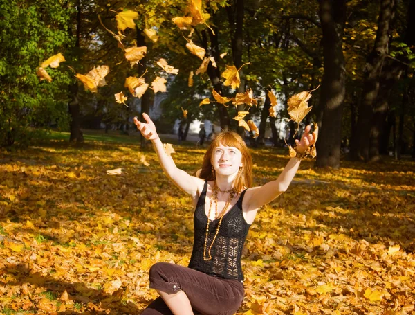 Жінка кидає осіннє кленове листя — стокове фото
