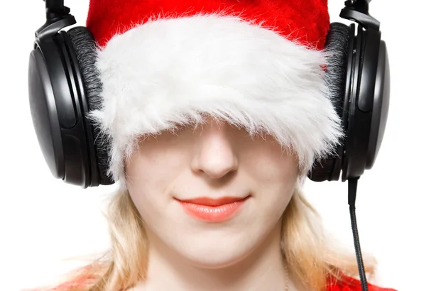 Junge Frau mit Weihnachtsmannhut hört Musik — Stockfoto