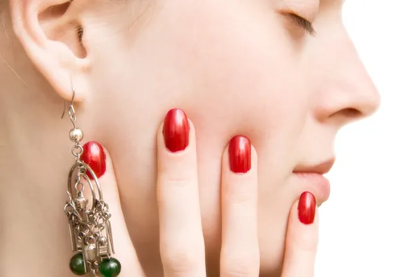 Молодая женщина лицо и рука с красными ногтями — стоковое фото