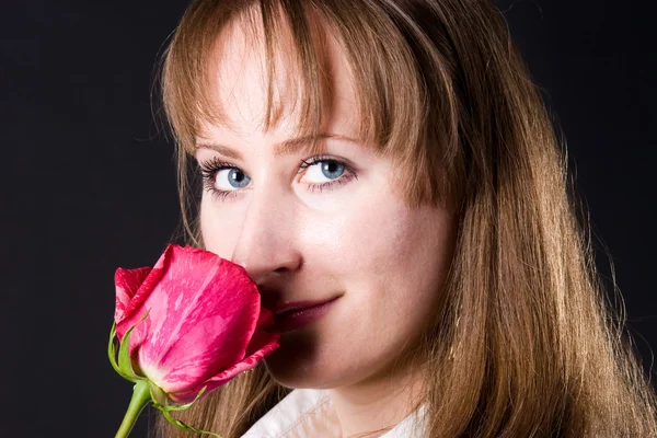 Jonge vrouw ruikende rode roos — Stockfoto