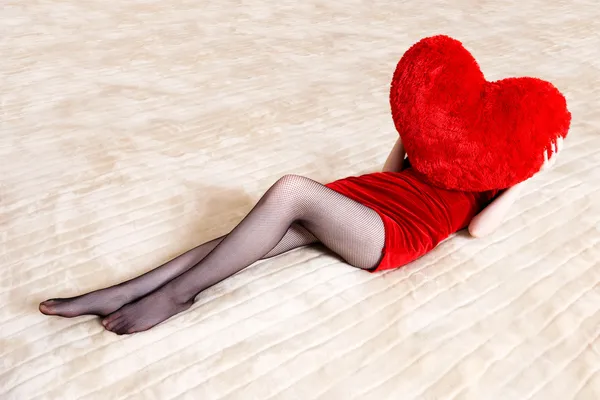 Νέα γυναίκα που κρατά την κόκκινη καρδιά μαξιλάρι — Φωτογραφία Αρχείου