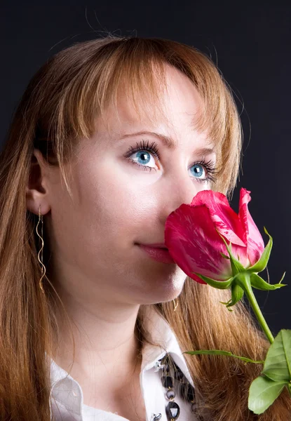 Νεαρή γυναίκα μυρίζοντας κόκκινο τριαντάφυλλο. — Φωτογραφία Αρχείου