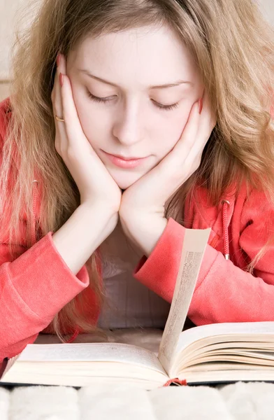 Ung kvinna läser en bok i en säng — Stockfoto