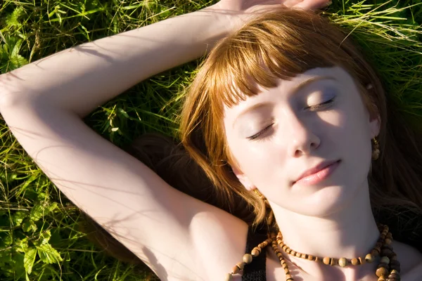 Ung kvinna som sover på ett grönt gräs — Stockfoto