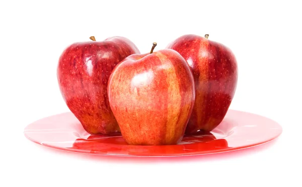 Trzy czerwone jabłka na czerwony talerz — Zdjęcie stockowe