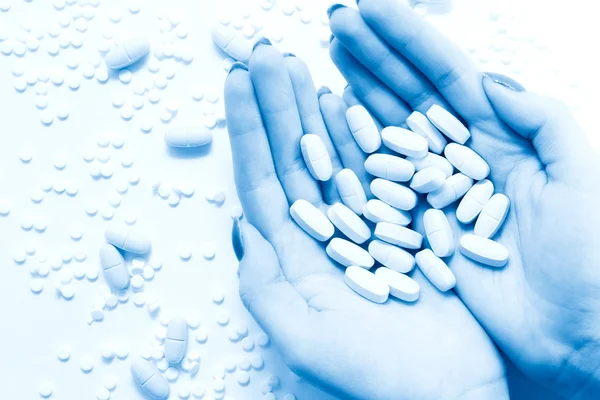 Main de femme avec beaucoup de pilules teinte bleue — Photo
