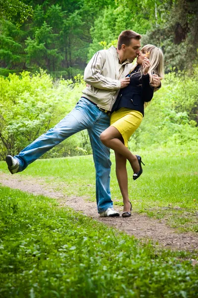 Unga lyckliga paret kyssas i en park — Stockfoto