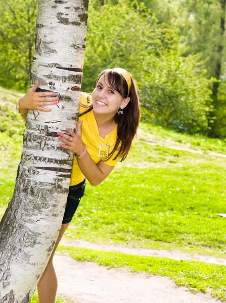Junge fröhliche Frau hält sich an Birke fest — Stockfoto