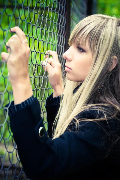 Junge Frau hält sich am Zaun fest — Stockfoto