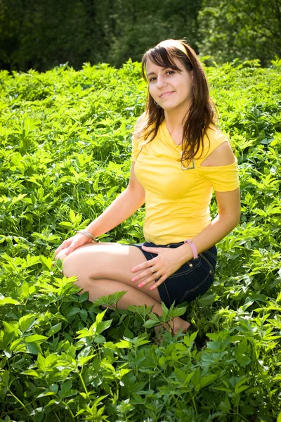 푸른 잔디에 앉은 젊은 여자 — 스톡 사진