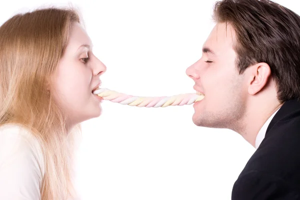 Muž a žena jíst jeden dlouhý sladkosti — Stock fotografie