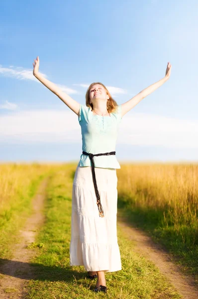 Junge glückliche Frau, die auf einem Feld geht — Stockfoto