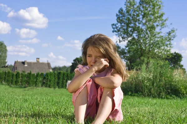 Crying little girl sitting on grass — Stock Photo, Image