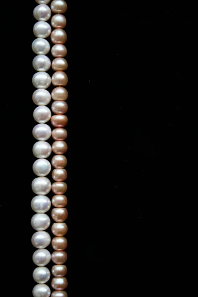 Біло-рожеві перлини на чорному фоні — стокове фото