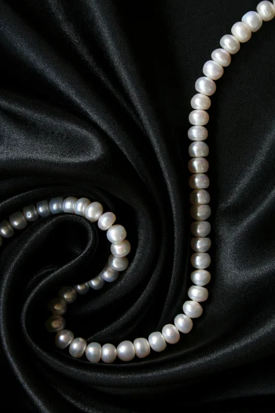 Pérolas brancas na seda preta como backgr — Fotografia de Stock