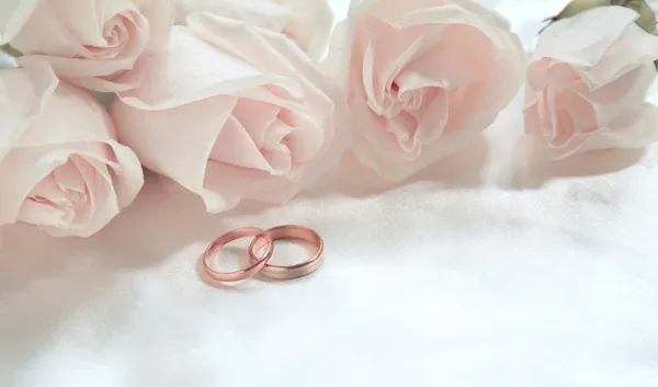 Anneaux de mariage et roses comme fond — Photo