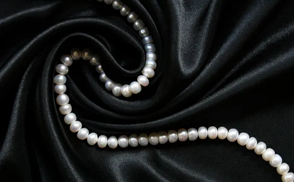 Białe perły na czarny jedwab jako tła — Zdjęcie stockowe