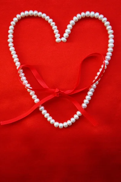 Coração de pérolas brancas em uma seda vermelha — Fotografia de Stock
