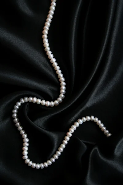 Белый жемчуг на черном шелке — стоковое фото