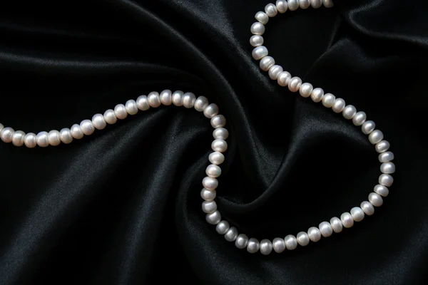 Pérolas brancas na seda preta — Fotografia de Stock