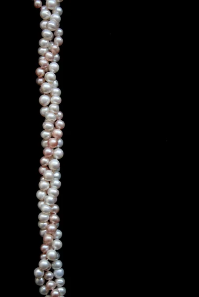 Weiße und rosa Perlen auf der schwarzen Seide — Stockfoto