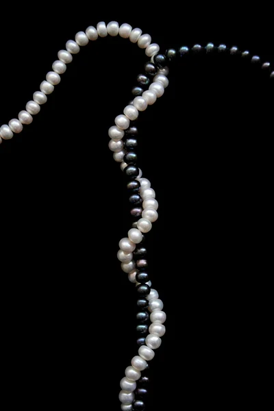 Vita och svarta pärlor på en svart — Stockfoto