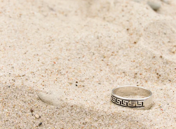 Stock image Silver ring lays on sand