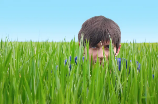 Νεαρός άνδρας που κρύβονται στο πράσινο γρασίδι — Φωτογραφία Αρχείου