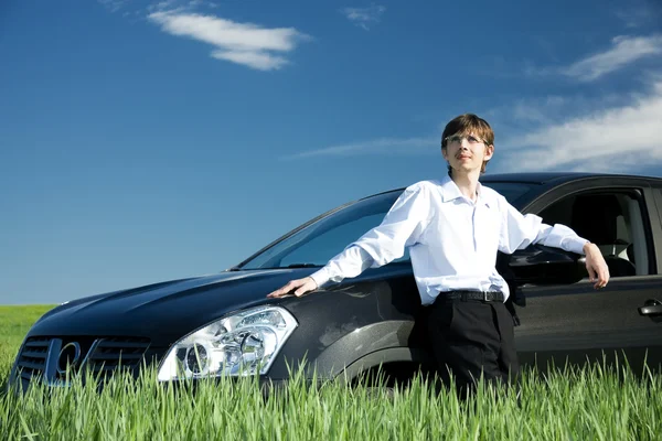 Businessman with car on grassland — Stock Photo, Image