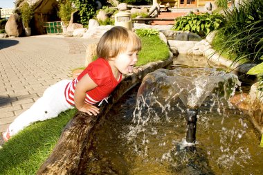 Cute little girl near a fountain clipart