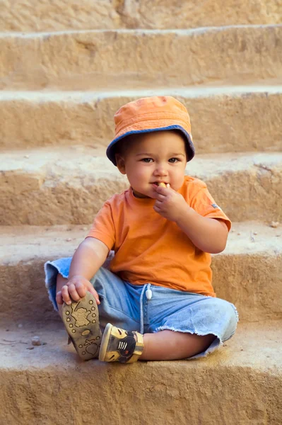 Orange klädda pojke sitter på stegen och — Stockfoto