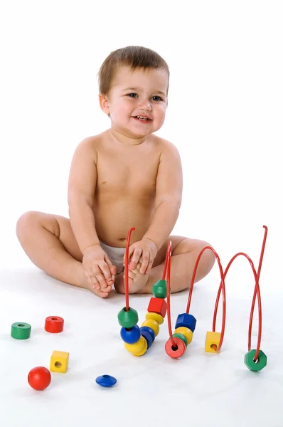 Menino sentado e rindo perto de seus brinquedos — Fotografia de Stock