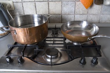 Pan and frying-pan at a gas-stove clipart