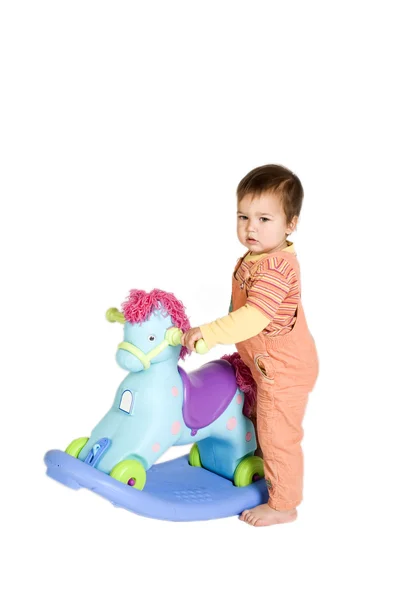 Laranja vestido bebê perto de cavalo de balanço — Fotografia de Stock