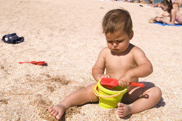 Serious tanned boy playing on the beach — Stock Photo, Image