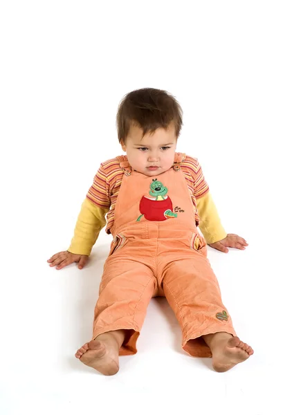 Barfota orange klädda pojke sitter en Stockbild