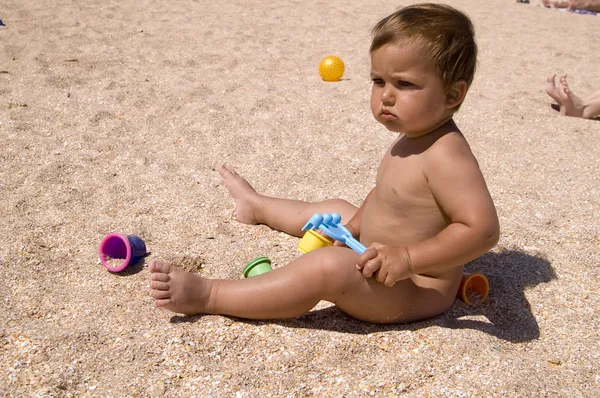 Ernstige gelooid jongen spelen op het strand Stockfoto