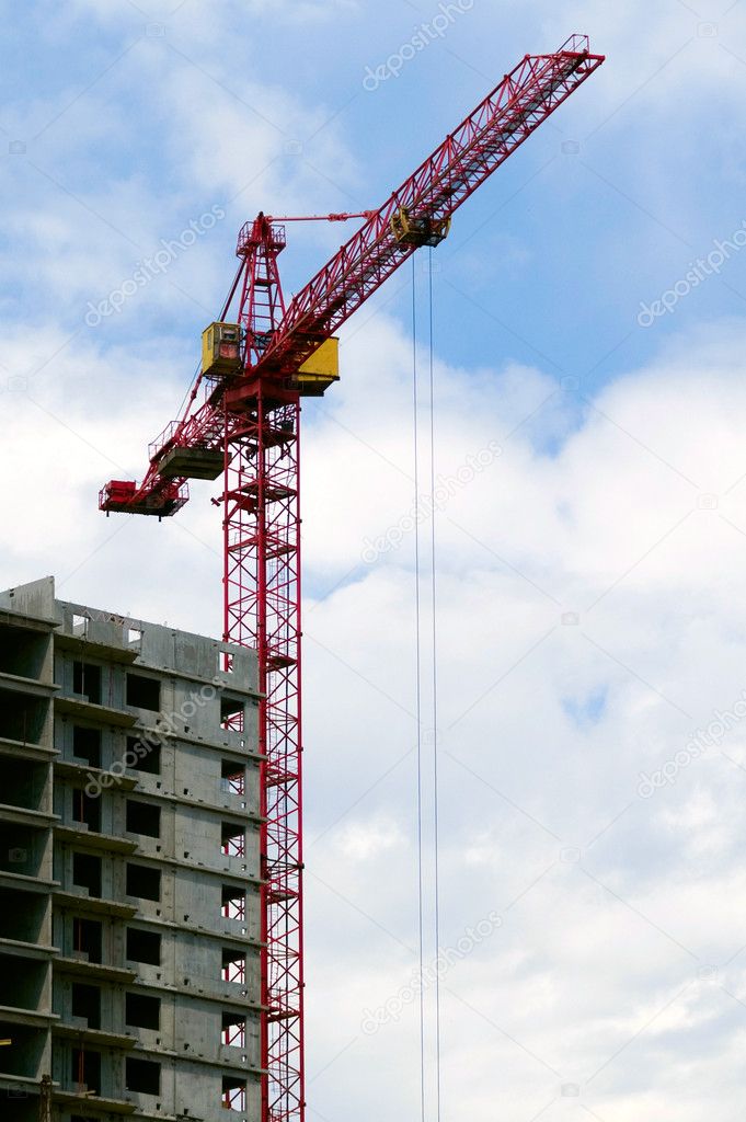 Building crane aganist cloudy sky and bu