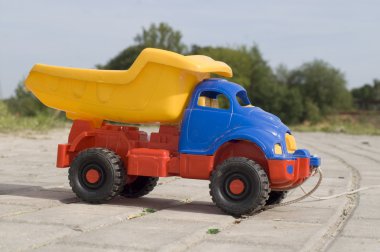 Baby toy dump truck on sunny road clipart