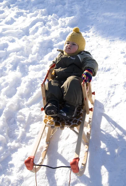 Baby in green coat has rest in sled — Stock Photo, Image