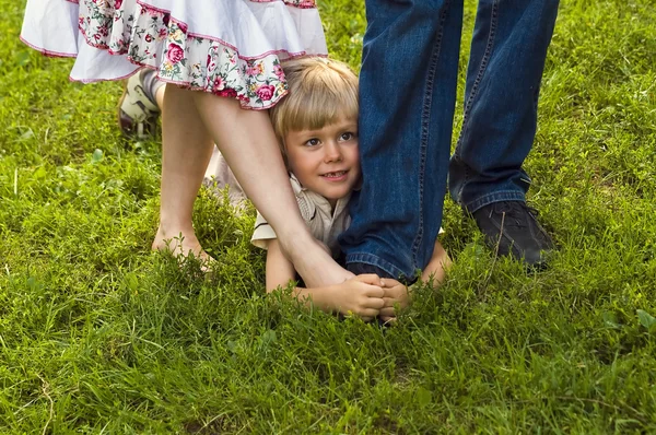 Garçon heureux caché dans les jambes des parents — Photo