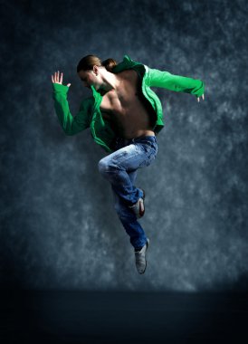 Modern dancer poses in front of the old dirty wall clipart